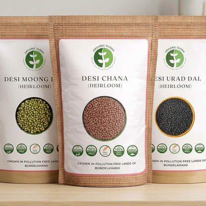 Three packages of heirloom seeds labeled 'Desi Moong', 'Desi Chana', and 'Desi Urad Dal' on a wooden surface.